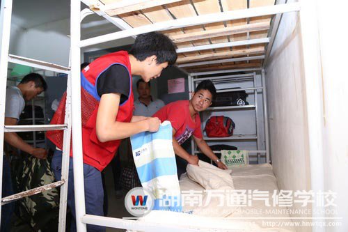 新生在紅馬甲學(xué)長(zhǎng)的幫助下整理床位